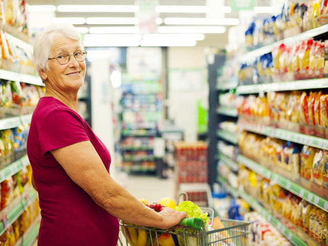 Senior shopping at a grocery store and comparing food prices